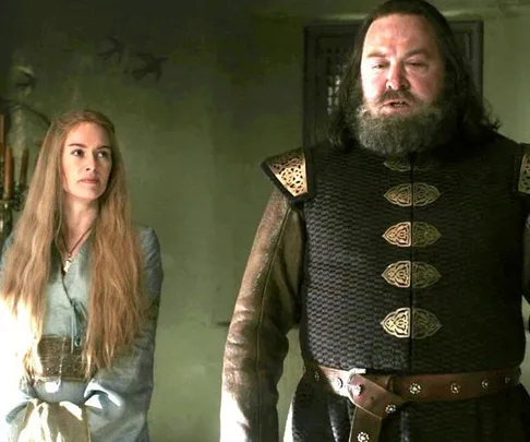 Cersei Lannister and Robert Baratheon from Game of Thrones, standing indoors, she looks towards him while he speaks.