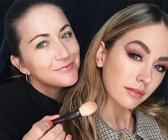 Makeup artist applying finishing touches with a brush on a model with glamorous makeup.