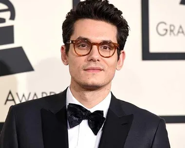 Man with dark hair and glasses wearing a black tuxedo, standing at an award event.