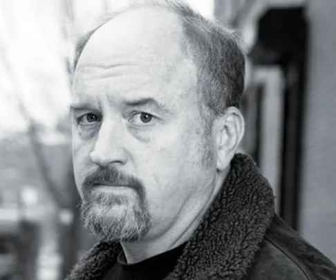 Black-and-white photo of a middle-aged man with a receding hairline and goatee, looking serious in a city street background.