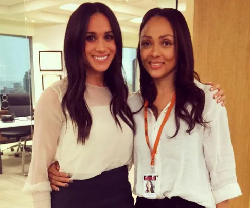 Meghan Markle and another woman on the set of "Suits" in an office setting.