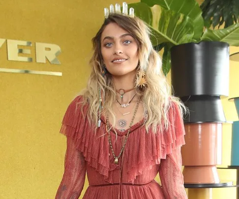 Paris Jackson in a rust-colored, ruffled dress with layered necklaces and a crystal headpiece, posing at Melbourne Cup event.