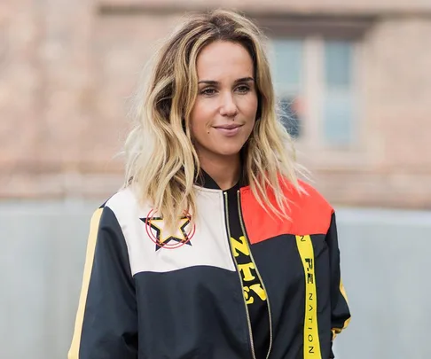 Image of Pip Edwards wearing a colorful jacket, with a star emblem, smiling while standing outdoors.