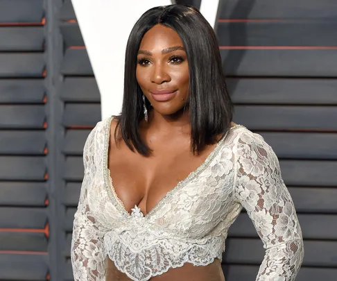 Woman in a white lace dress with long black hair at a formal event.