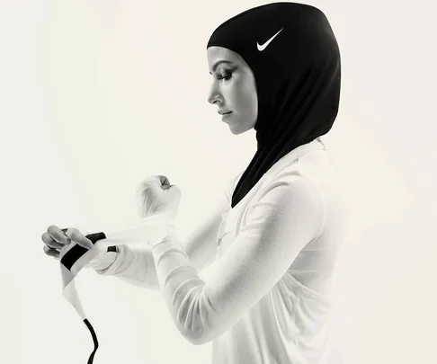 Woman in a Nike sports hijab wrapping her hands, side profile against a plain background.