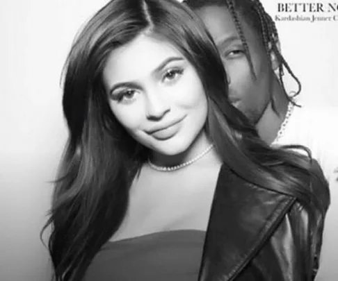 Black and white photo of a smiling woman with long hair standing in front of a man with braided hair.