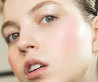 Close-up of a person with smooth, glowing skin, showcasing clear pores and subtle makeup.