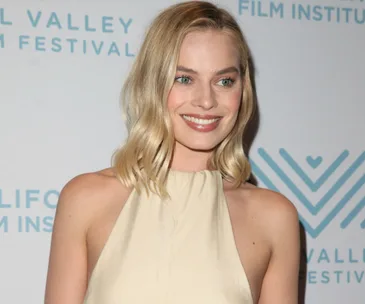 Margot Robbie at the Mill Valley Film Festival, smiling, with a light-colored dress and blonde hair worn loose.