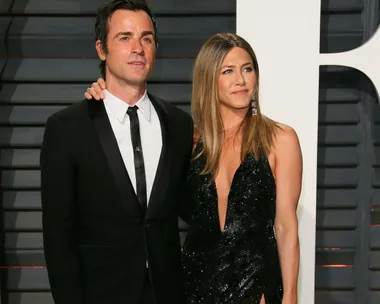 A couple dressed formally, attending a red carpet event; the woman is in a black dress and the man is in a black suit.