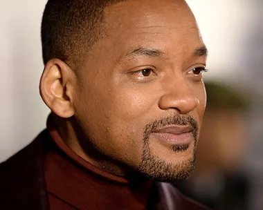 A close-up portrait of Will Smith wearing a maroon turtleneck and dark jacket.