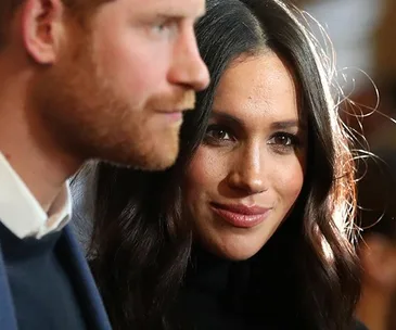 A close-up image of a woman's face with dark hair and a man with a beard, both gazing in the same direction.