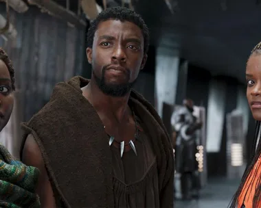 Characters Nakia, T'Challa, and Shuri from "Black Panther" are standing side by side in a tech-filled hallway.