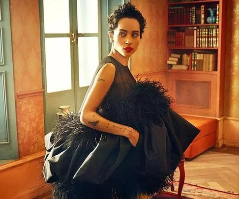 Zoe Kravitz, as Leta Lestrange in "Fantastic Beasts: The Crimes of Grindelwald," in a room with bookshelves, wearing a black feathered dress.