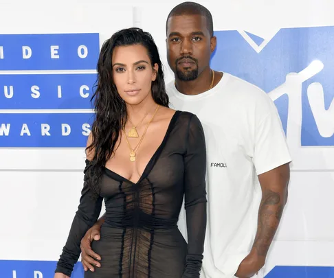 A woman in a black dress and a man in a white shirt pose at the MTV Video Music Awards.