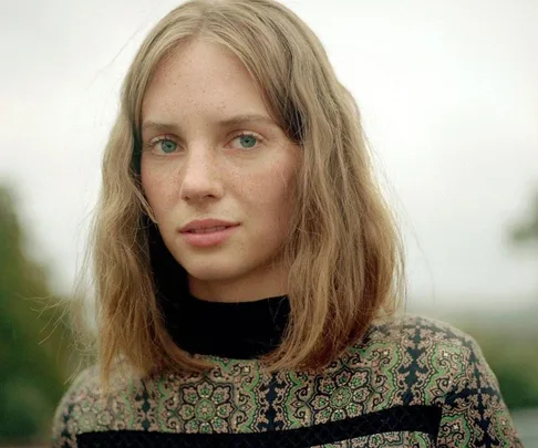 Portrait of Maya Hawke, known for her role as Robin Buckley in Stranger Things season 3, wearing a patterned high-neck top.