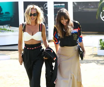 Two women walking outdoors at the Australian Grand Prix Mercedes-Benz Ladies Day, dressed in stylish outfits and smiling.