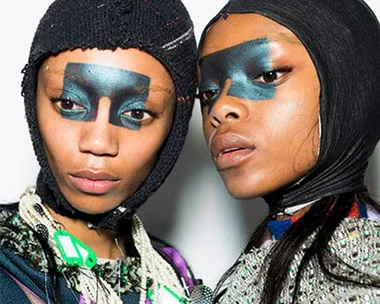 Models with bold, dark eye makeup and knit head coverings at London Fashion Week AW18.