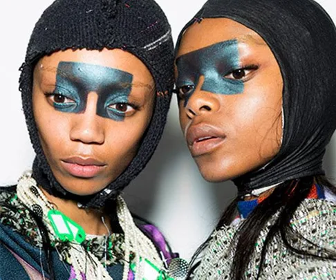 Models with bold, dark eye makeup and knit head coverings at London Fashion Week AW18.