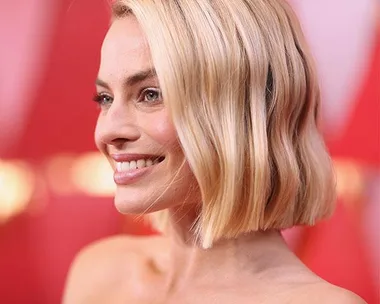 Smiling woman with short, blonde hair on the Oscars 2018 red carpet, wearing a strapless outfit.