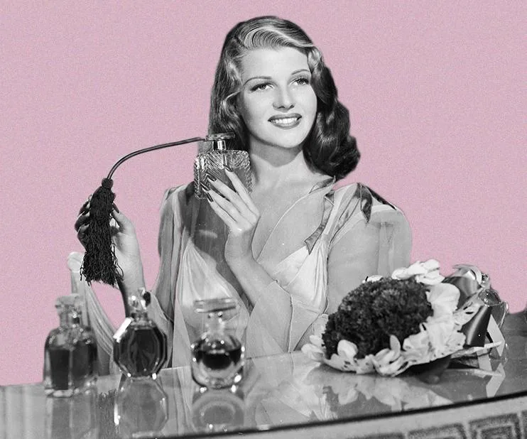 A black-and-white photo of a woman holding a perfume atomizer surrounded by perfume bottles against a pink background.