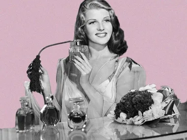 A black-and-white photo of a woman holding a perfume atomizer surrounded by perfume bottles against a pink background.