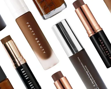 Various foundation products for dark skin tones from brands like Fenty Beauty, NARS, and Bobbi Brown arranged on a white background.