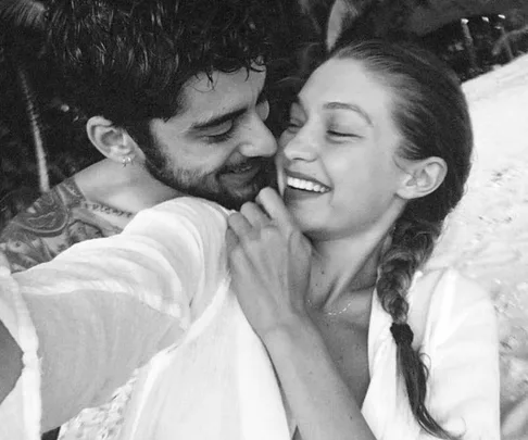 A man and woman smiling, embracing each other in a black and white photo, appearing happy and affectionate.