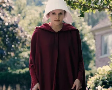 A woman in a red cloak and white bonnet stands outside in a scene from "The Handmaid's Tale."