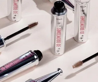 Benefit Cosmetics 3D BROWtones bottles and brushes arranged aesthetically on a light surface.