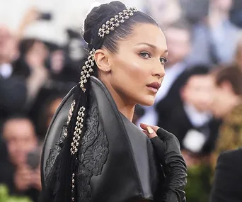 Elegant woman in detailed black gown with jeweled hair at Met Gala 2018, turning head to the side.