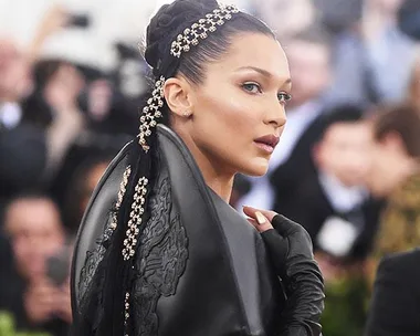 Elegant woman in detailed black gown with jeweled hair at Met Gala 2018, turning head to the side.