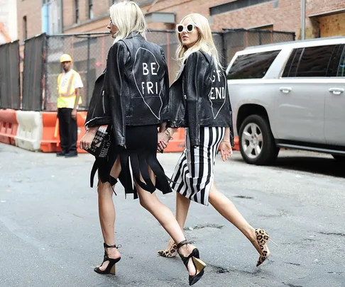 Two women walking, wearing matching black leather jackets with "BEST FRIENDS" split between them.