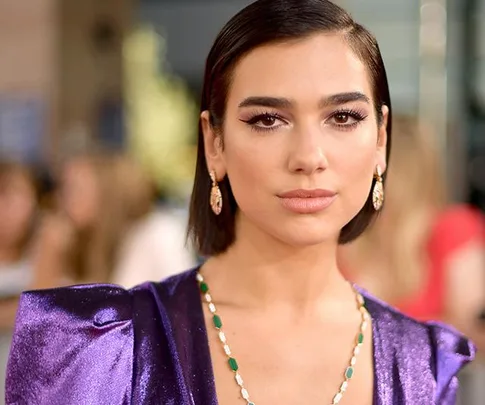 Dua Lipa in a purple dress on the red carpet at the 2018 Billboard Music Awards.