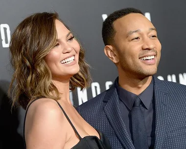 Chrissy Teigen and John Legend smiling together at a formal event.