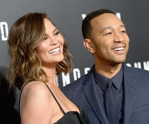 Chrissy Teigen and John Legend smiling together at a formal event.