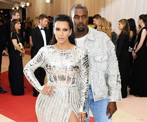 Two individuals in stylish silver and denim outfits pose on the red carpet at a formal event.