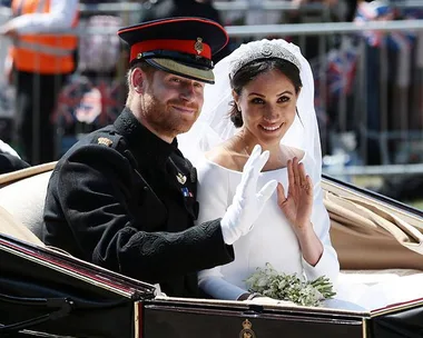 Prince Harry and Meghan Markle in wedding attire, waving from a carriage.