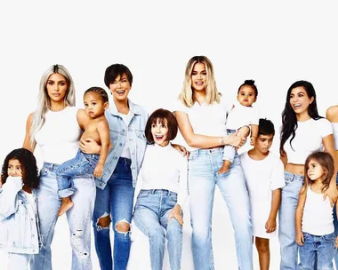 A family group photo, all wearing white tops and jeans, standing together and smiling in front of a plain white background.