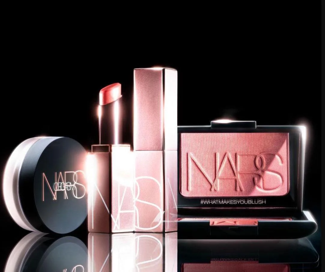 NARS Orgasm collection featuring blush, lipstick, lip gloss, and pressed powder against a black background.