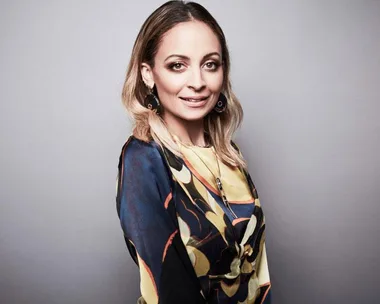 Nicole Richie posing in a colorful patterned dress for a beauty routine article, light brown hair, smiling at the camera.