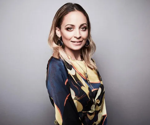 Nicole Richie posing in a colorful patterned dress for a beauty routine article, light brown hair, smiling at the camera.