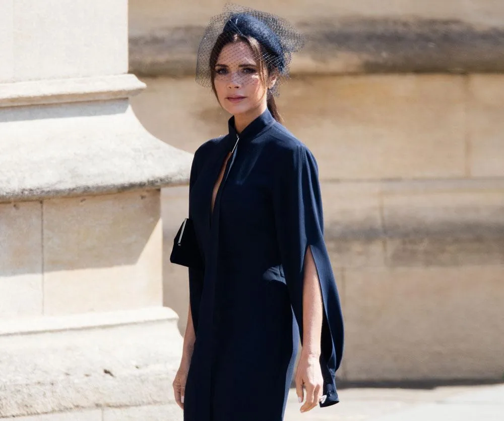 Victoria Beckham at the 2018 royal wedding in a navy dress with split sleeves and a netted fascinator.