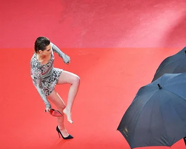 Kristen Stewart removing her high heels on the red carpet at Cannes Film Festival.