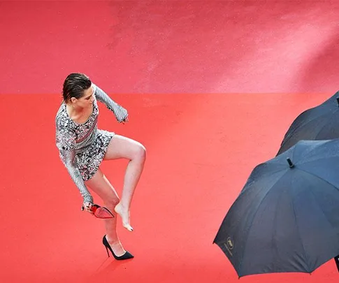 Kristen Stewart removing her high heels on the red carpet at Cannes Film Festival.