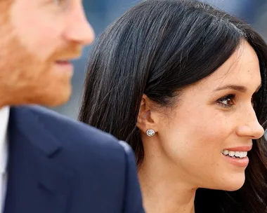 Image of two individuals, a woman with dark hair and a man with red hair, smiling and looking towards the right.