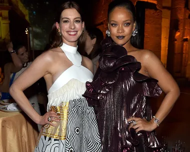 Anne Hathaway and Rihanna in stylish dresses smile and pose together at a formal event.