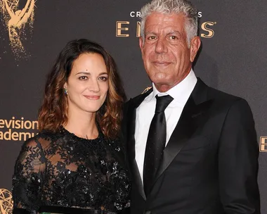 Two individuals pose together, dressed formally, in front of a "Television Academy Emmys" backdrop.