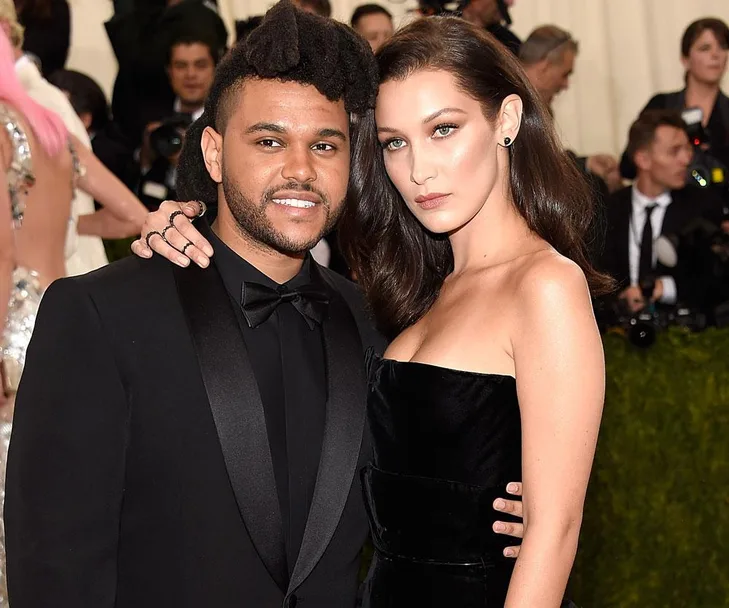 A couple poses together in formal attire at a glamorous event, surrounded by other guests and photographers.