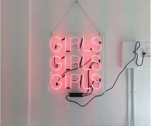 Neon sign reading "GIRLS GIRLS GIRLS" in pink, hanging on a wall with black power cord.