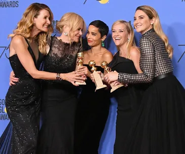 "Big Little Lies cast members in black dresses, holding Golden Globe awards at an event, smiling and celebrating together."